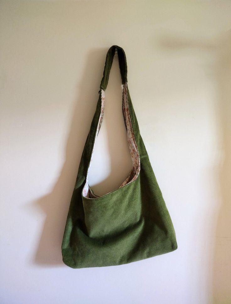 A small crescent-shaped bag made with patches of fabric, in beige, blue, and purple. A small teal panda keychain is hanging off of its zipper.